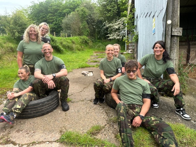 Group of smiling people sitting in a yard dressed in camouflage