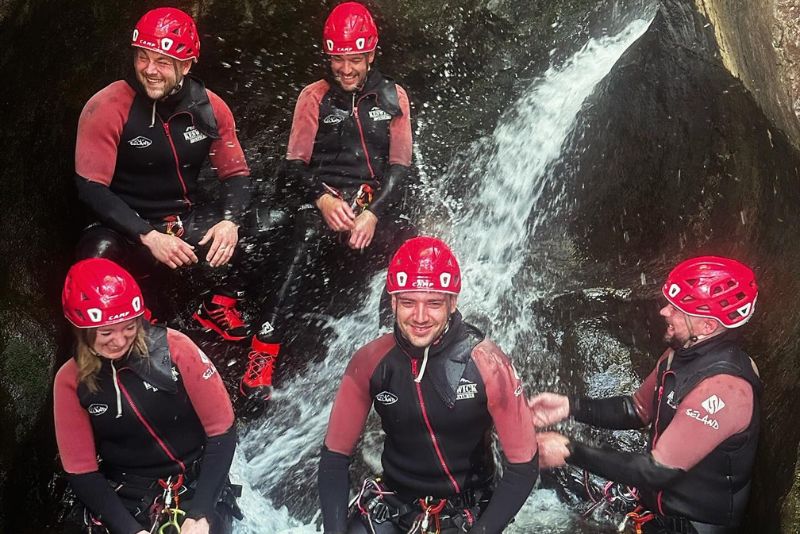Group of me nand women laughing in front of a small waterfall in a ghyll