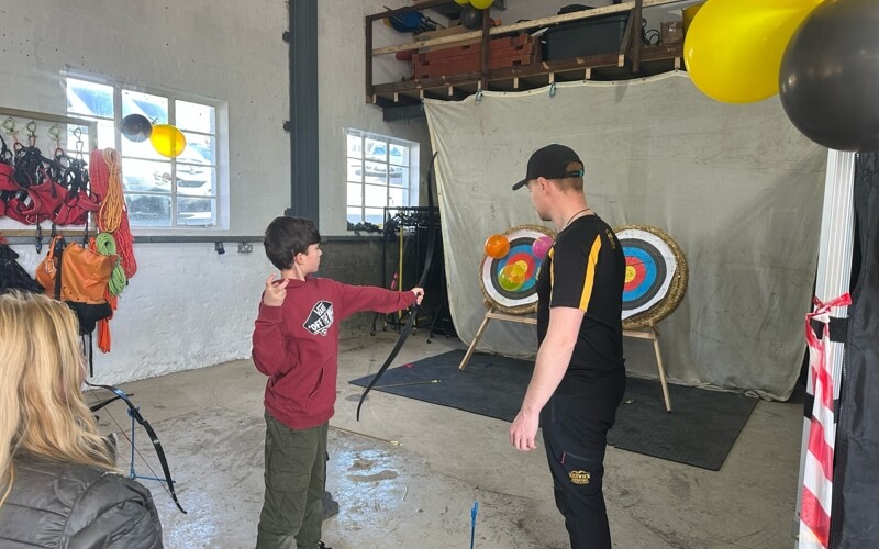 Boy shooting balloons on an archery target 