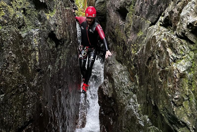 A man climbing down a narrow canyon