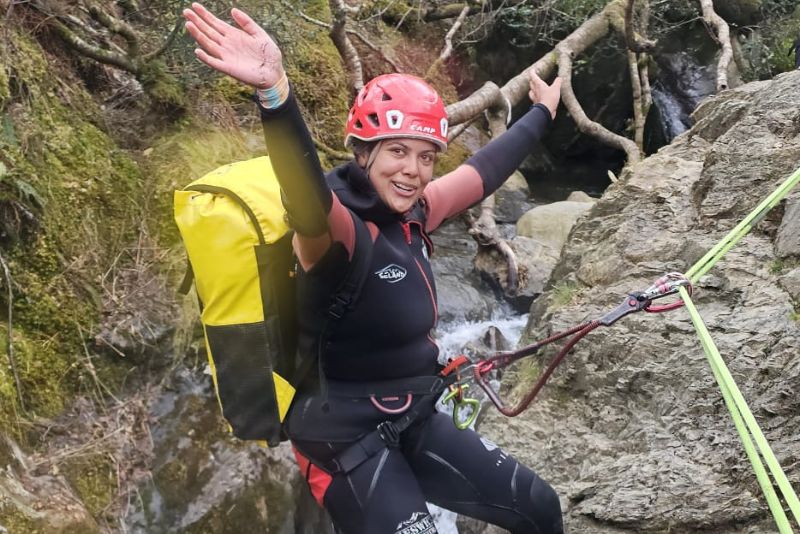 Woman smiling with arms raised while canyoning