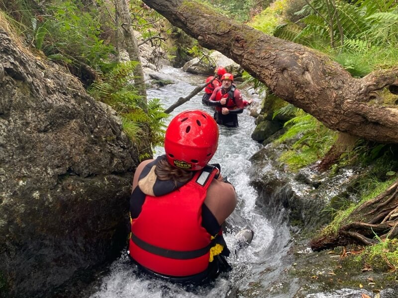 People sliding down a water slide in a ghyll
