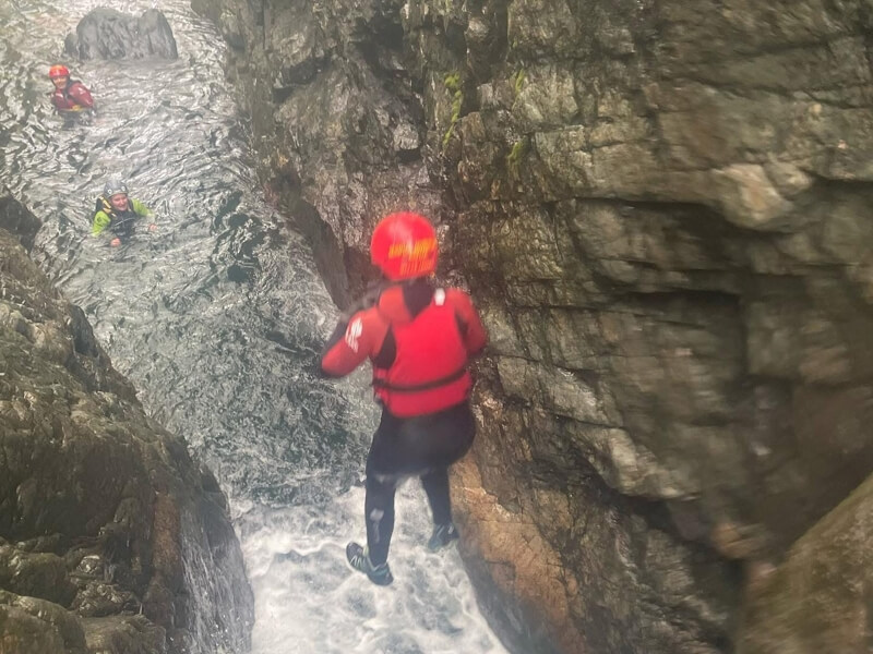 Kid jumping off a waterfall into a river gorge
