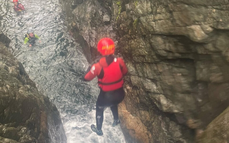 A person jumping off a waterfall into Church Beck Canyon