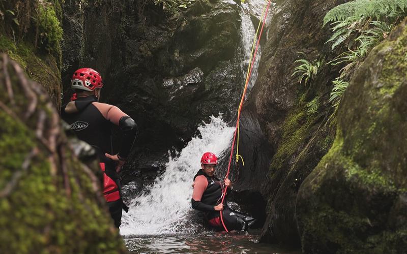 Man abseiling down a waterfall in a canyon
