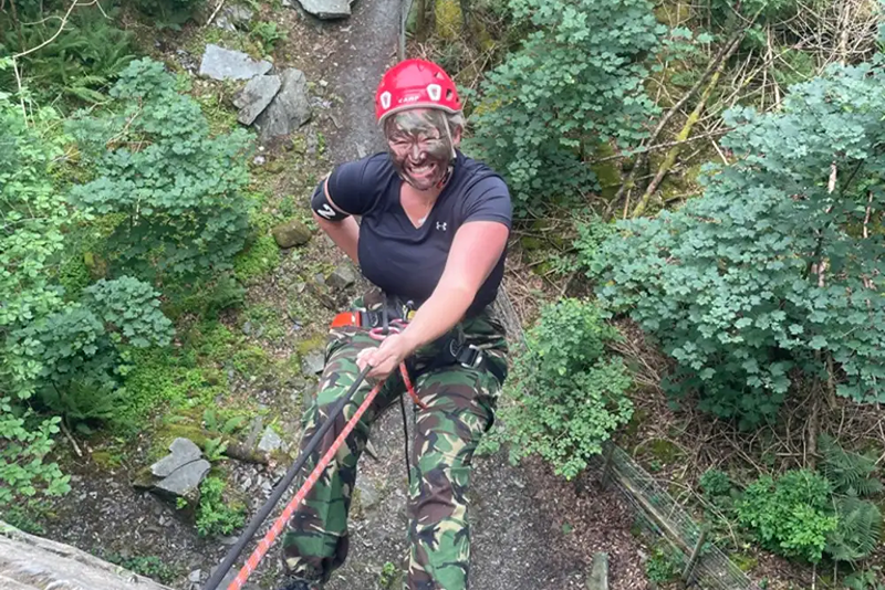 Woman laughing as she abseils down a cliff