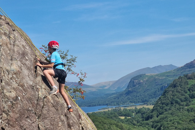 Boy rock climbing and looking out over the Lake District