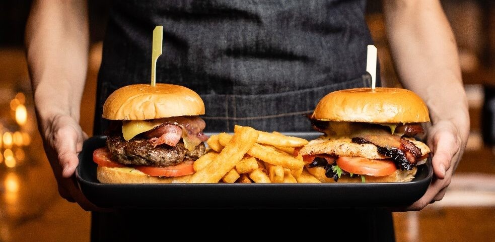 Waiting staff holding a platter that contains two burger and some chunky chips