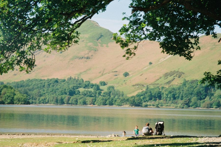 Family sitting by Derwentwater in the Lake District, with Catbells in the background