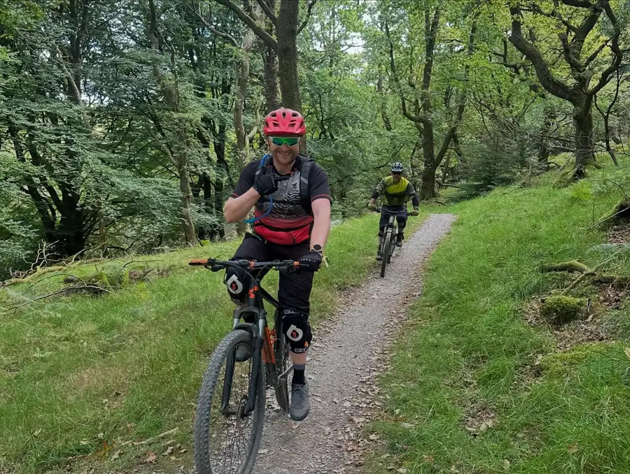 Two men mountain biking through the woods