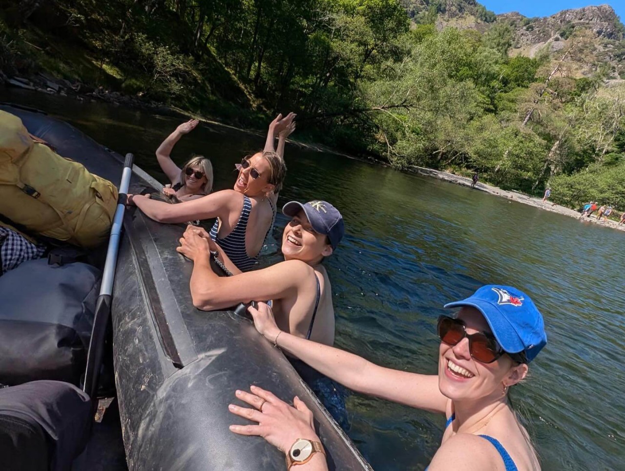 Four women in the water smiling and waving