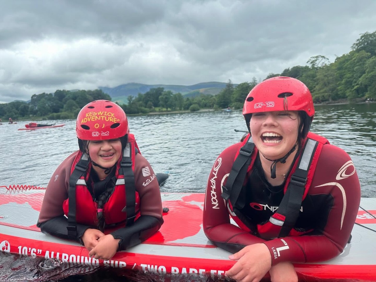 Two teenagers laughing on a paddleboard on Derwentwater