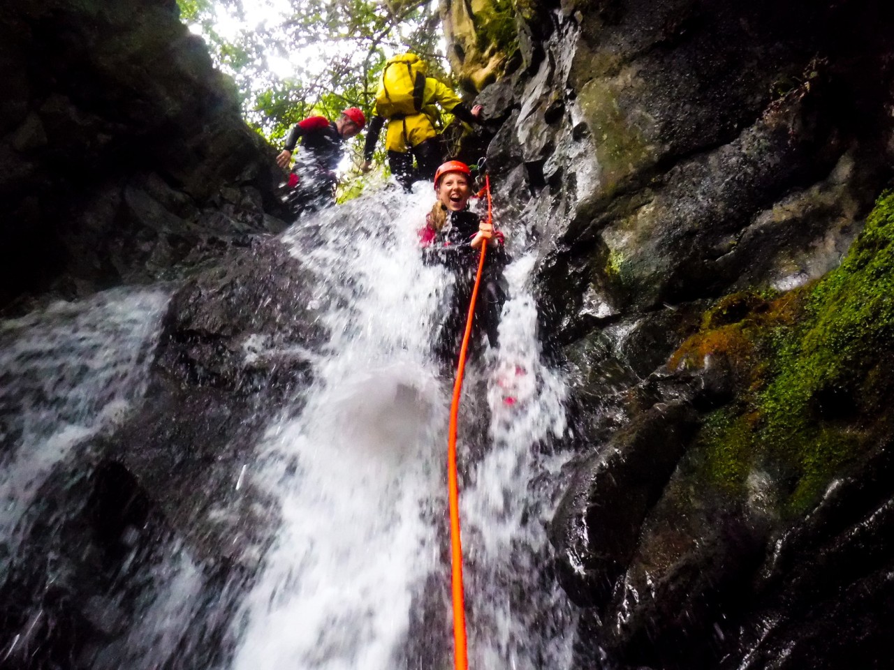 Teenager laughing while abseiling down a waterfall